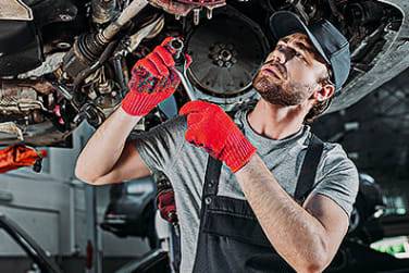 An engineer working on a Jeep Gladiator which has been lifted on a ramp